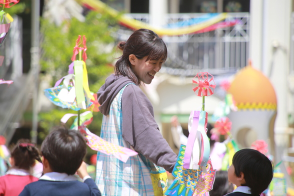 先生と園児が、一緒に滑り台を滑っている